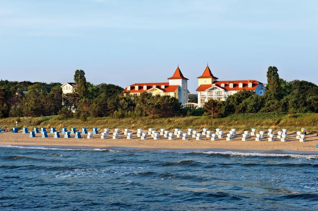 einen Strand mit weißen Sonnenschirmen und Stühlen darauf in der Unterkunft Hotel Kleine Strandburg - Adults Only in Zinnowitz