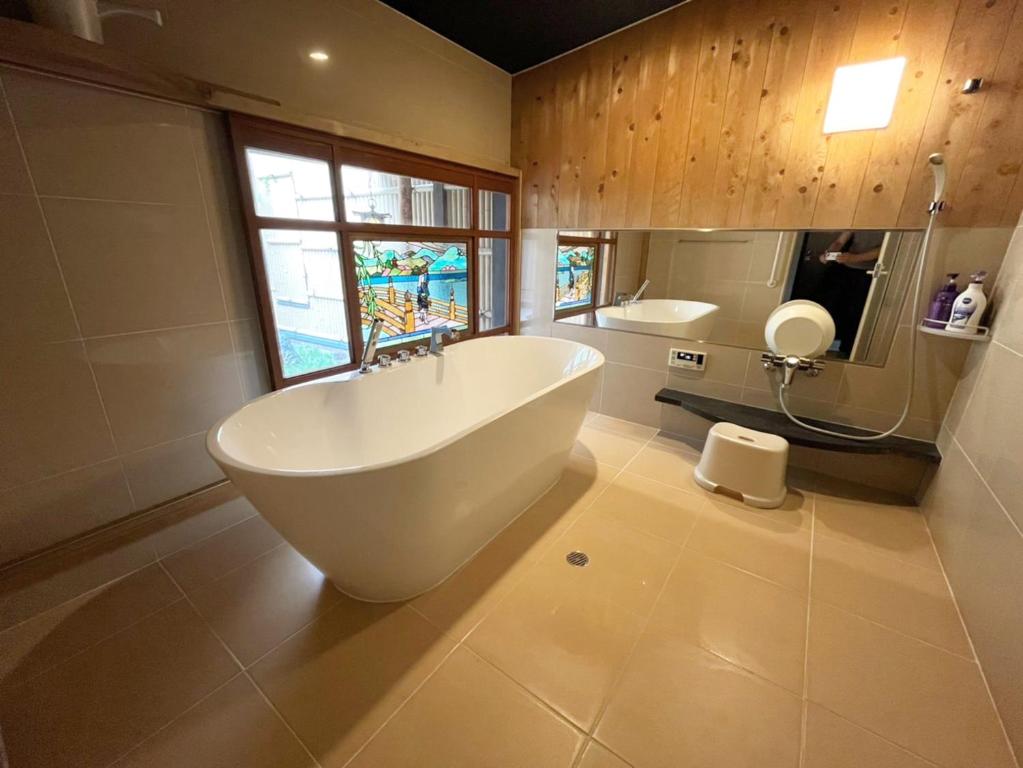 a bathroom with a large tub and a window at Takeya Kitano Honkan in Kyoto