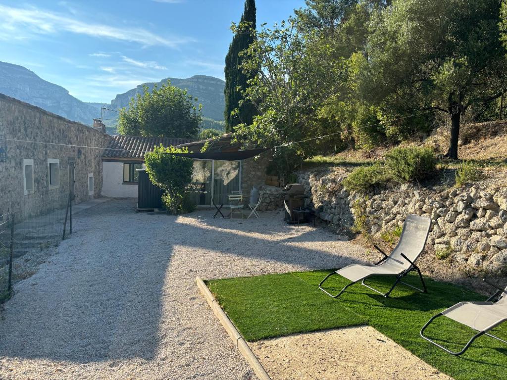 une cour avec deux chaises et un mur de pierre dans l'établissement Maisonnette face au Garlaban, à Roquevaire