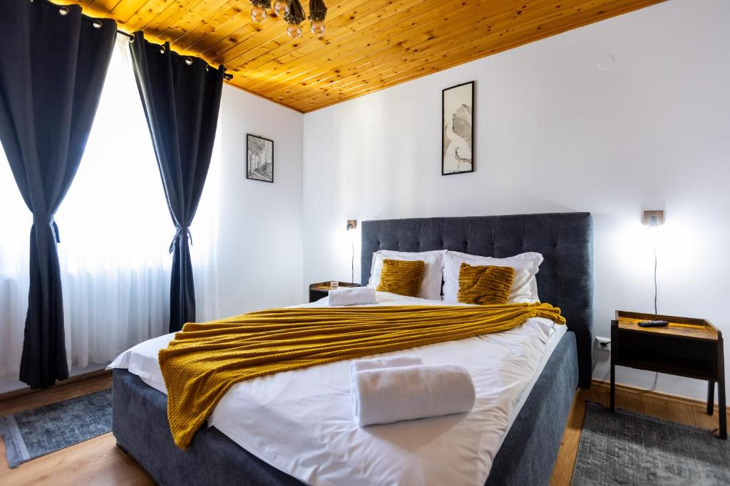 a bedroom with a large bed with a yellow blanket on it at Villa Falco Bianco in Buşteni