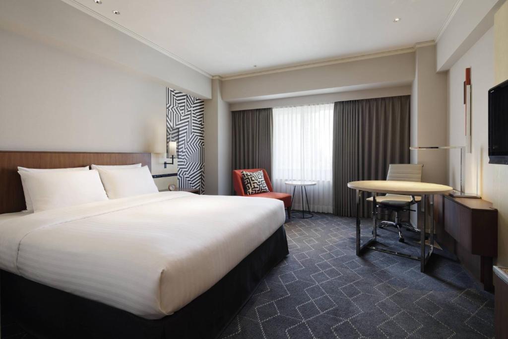 a hotel room with a large bed and a table at Courtyard by Marriott Shin-Osaka Station in Osaka