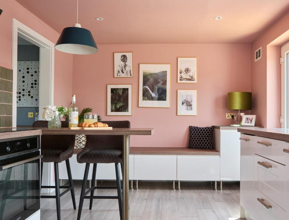 a kitchen with pink walls and a wooden table at Whimsical Haunt in West Malling