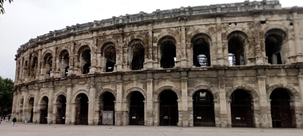 un grand bâtiment en pierre avec de nombreuses fenêtres dans l'établissement La jade wifi climatisation arènes, à Nîmes