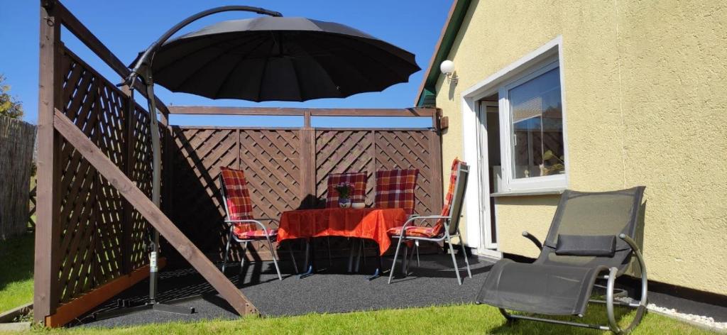 a patio with a table and chairs and an umbrella at Garten-Ferienhaus Biendorf OT Westenbrügge in Uhlenbrook