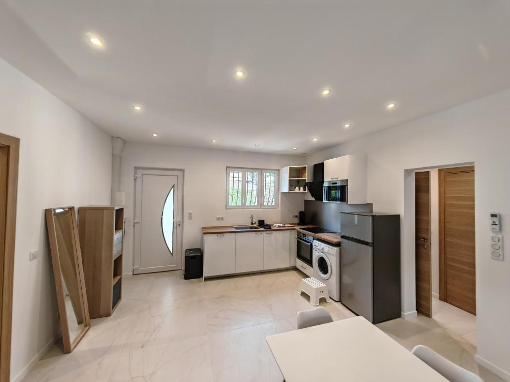 une grande cuisine avec des murs blancs et un sol blanc dans l'établissement Petite villa climatisée Jardin, à Vallauris