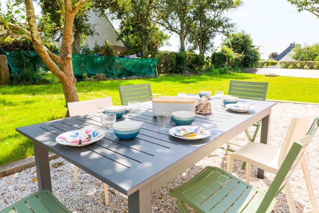 a blue table with plates and bowls on it at À 490m de la plage, maison neuve pour 8 in Trébérouant