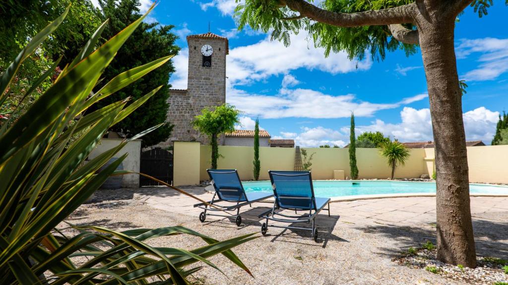 deux chaises au bord d'une piscine avec une tour d'horloge dans l'établissement Montclar, à Montclar