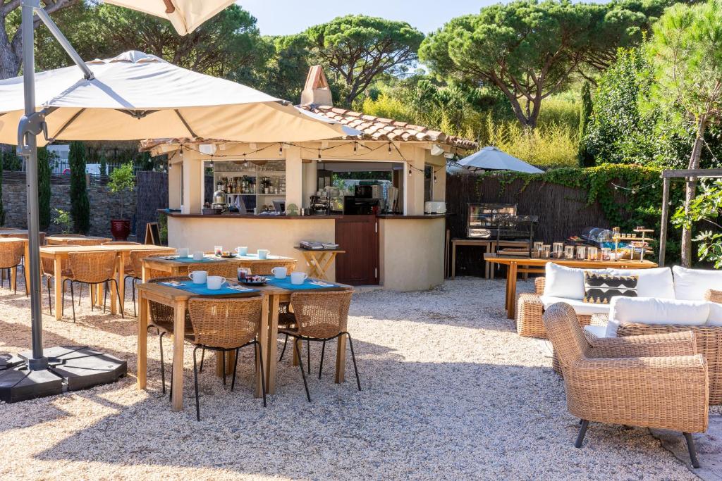 an outdoor patio with tables and chairs and a kitchen at Hôtel L'Escalet in Ramatuelle