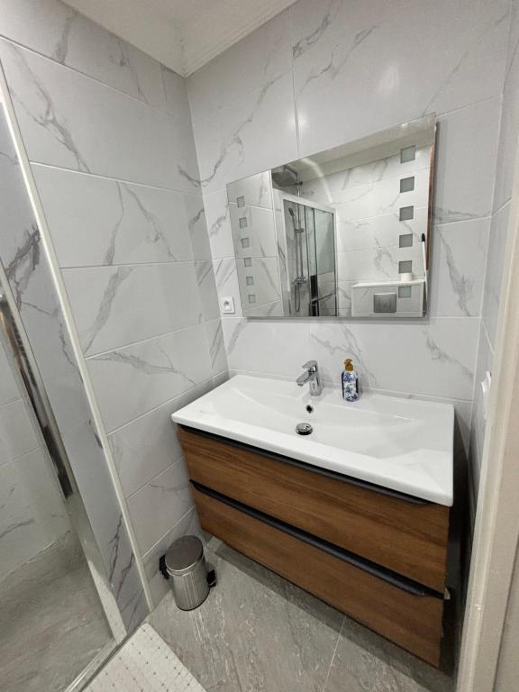 ein weißes Badezimmer mit Waschbecken und Spiegel in der Unterkunft Chaleureux t1 Aiguebelle in Randens