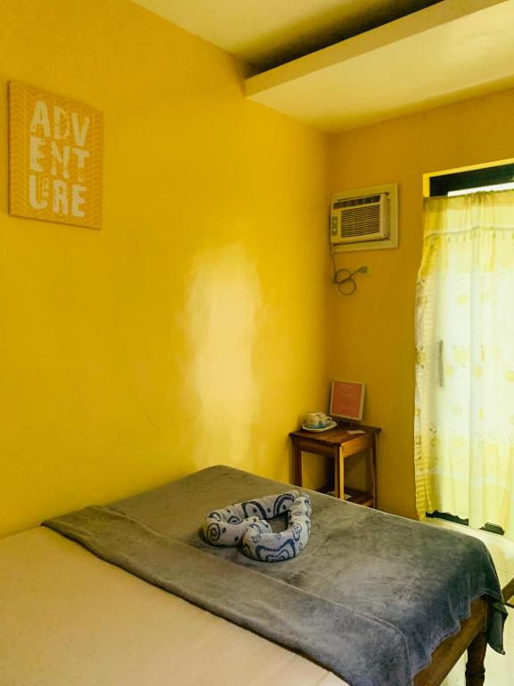 a room with a bed with a yellow wall at Francis Dale Lodge L7 in El Nido