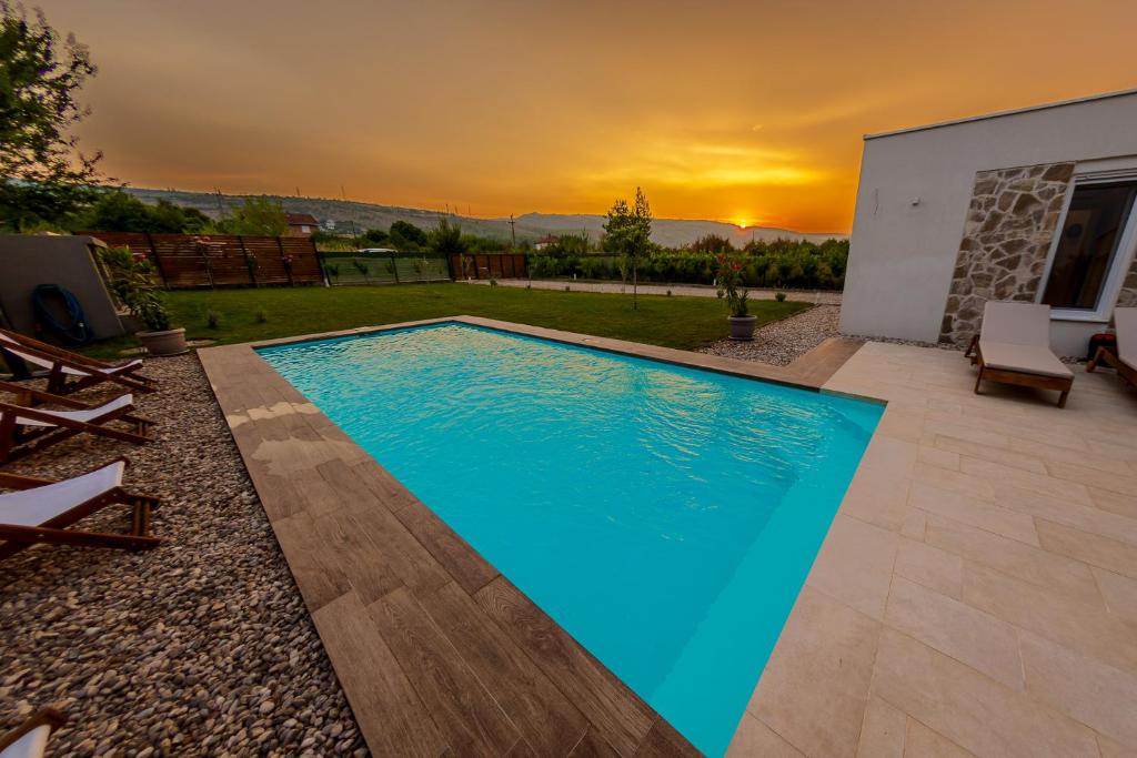 a swimming pool with a sunset in the background at Holiday Home Lara in Mostar