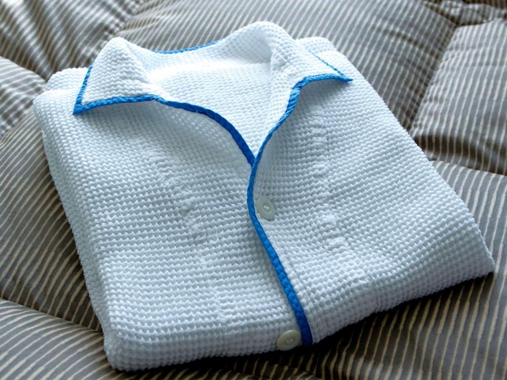 a white shirt with a blue collar sitting on a bed at Comfort Hotel Nara in Nara