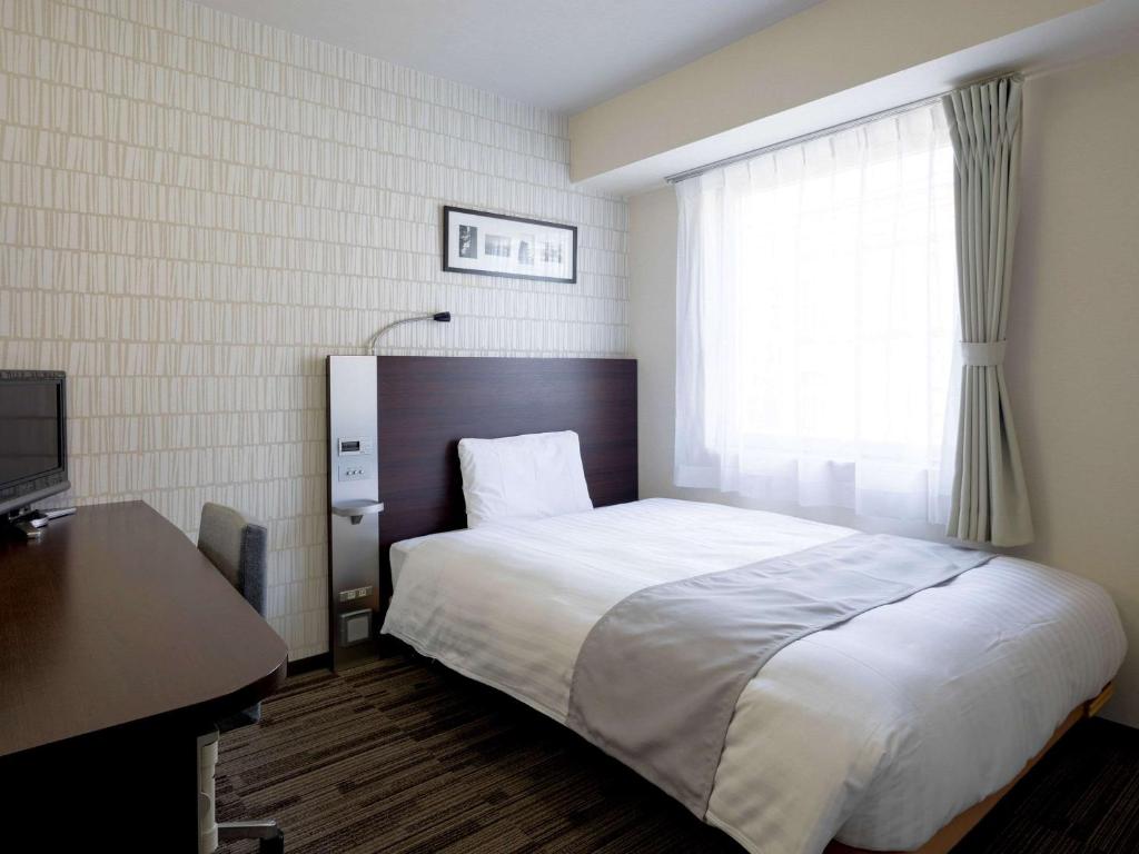 a bedroom with a bed and a desk and a window at Comfort Hotel Nara in Nara