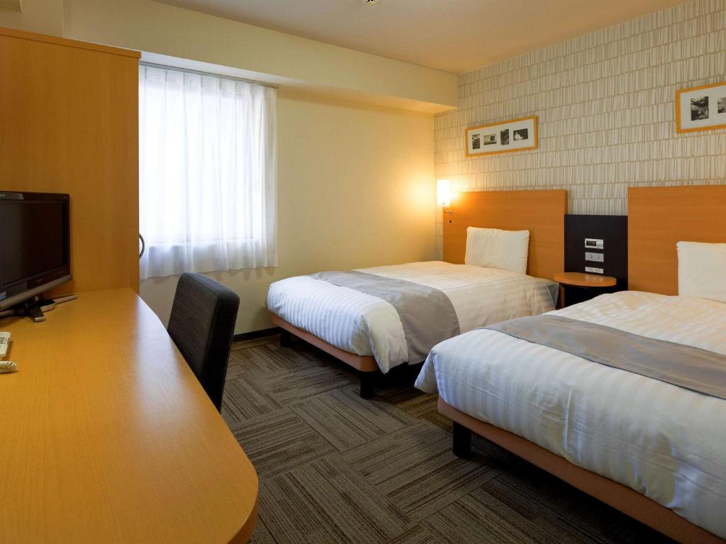 a hotel room with two beds and a desk at Comfort Hotel Nara in Nara