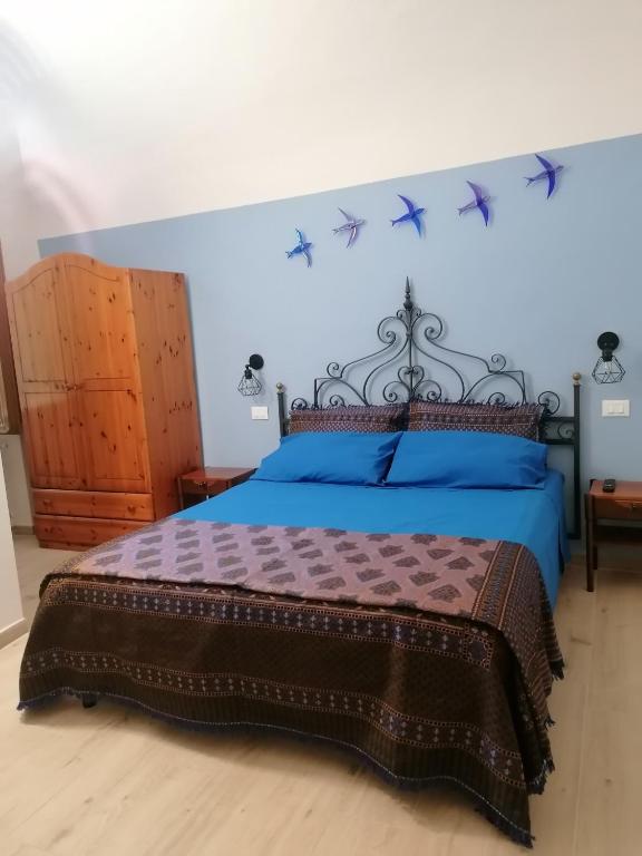 a bedroom with a bed with blue sheets and birds on the wall at Camera Rondini di Casa Mosaico in Volterra