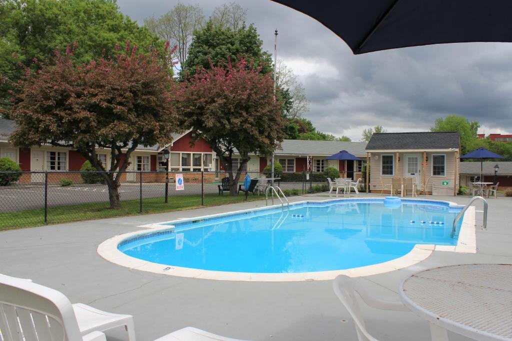a swimming pool with a table and chairs and an umbrella at Berkshire Inn in Pittsfield