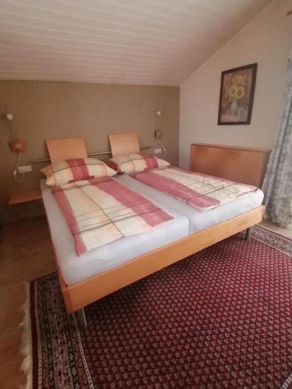 1 cama grande en un dormitorio con alfombra roja en Ferienwohnung am Rhein, en Koblach