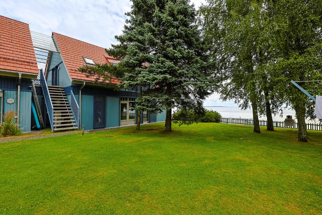 a house with a grass yard next to a building at Laikas Prie Marių Apartments Waterfront, by Cohost in Preila