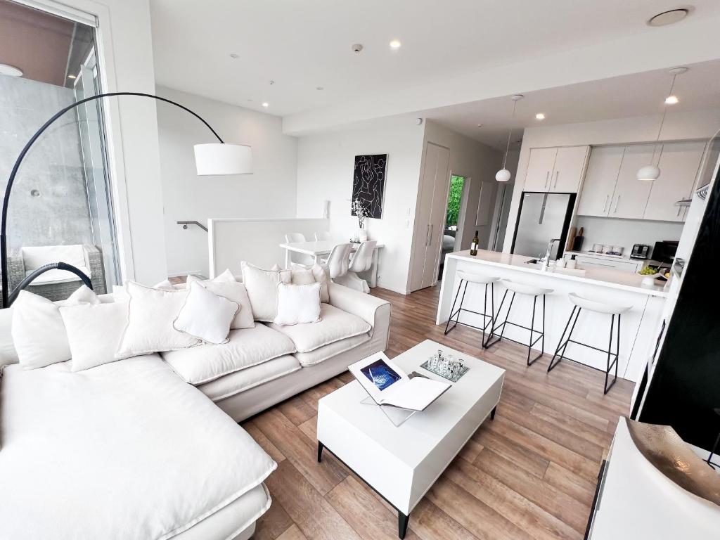 a living room with a white couch and a table at Luxury 2 Bedroom Apartment with cocktail bar and espresso machine in Auckland