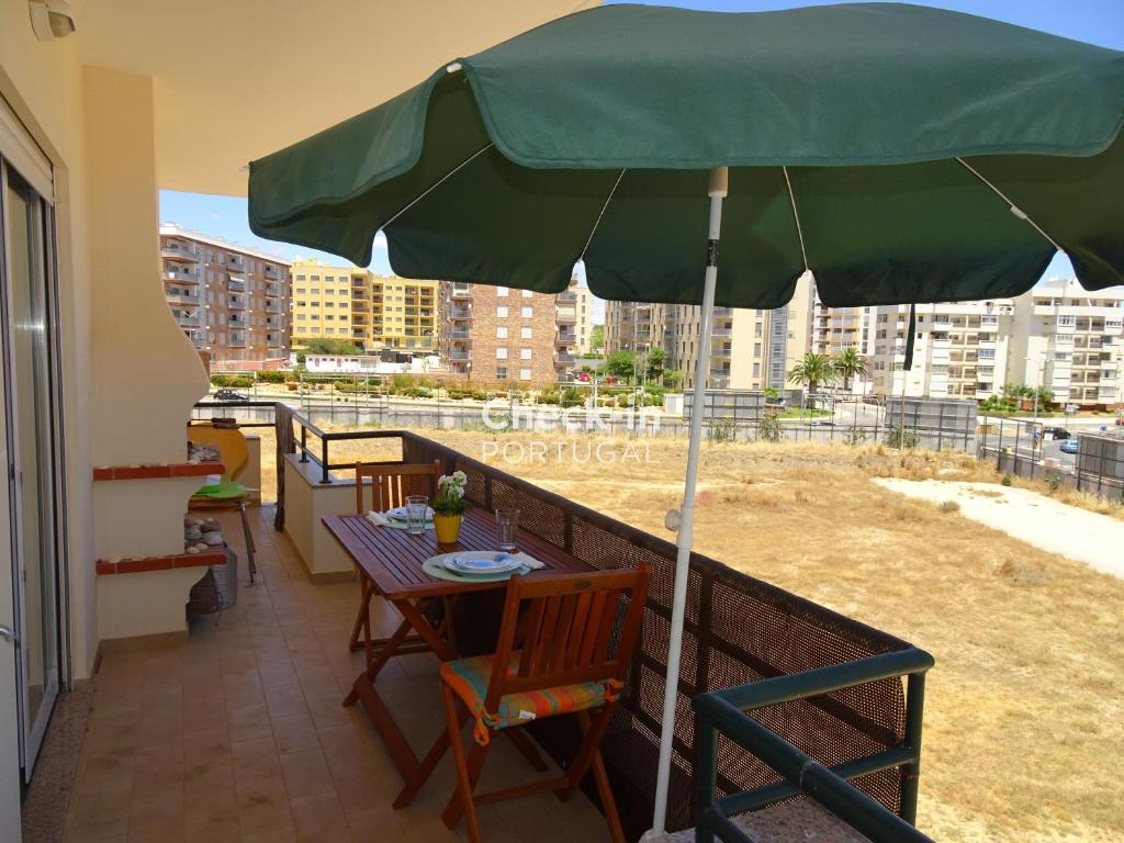 a table with a green umbrella on a balcony at Pera by Check-in Portugal in Armação de Pêra