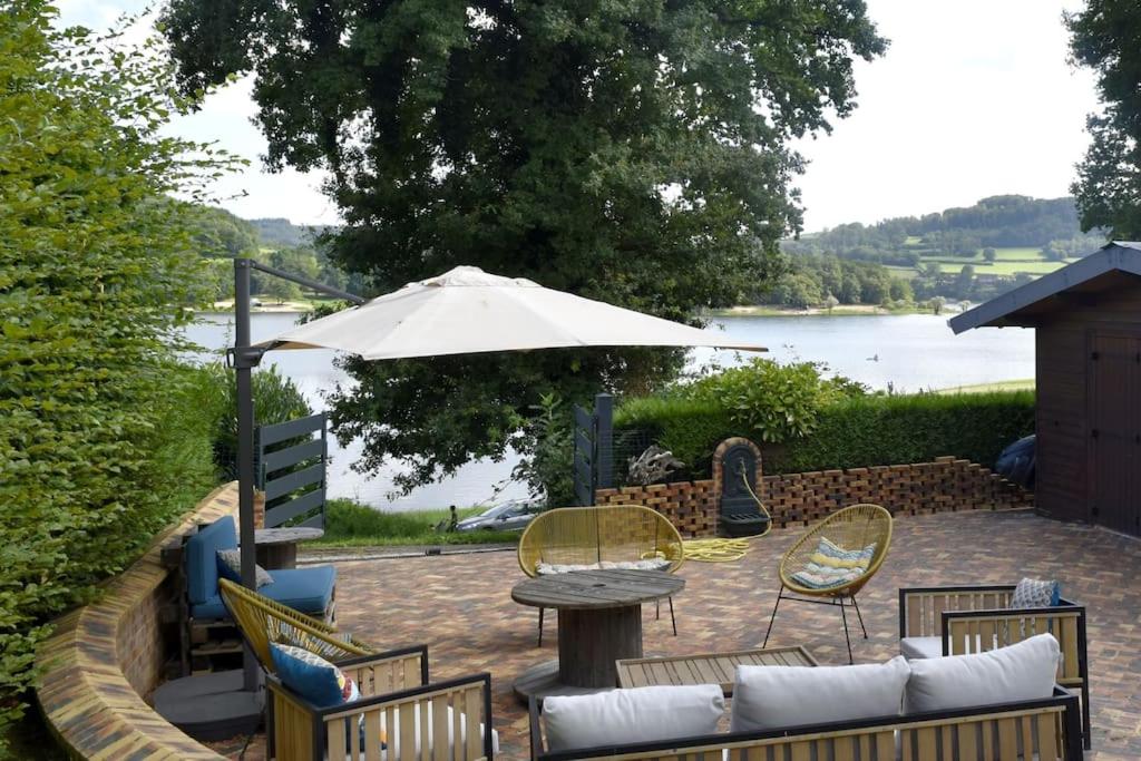 a patio with a table and chairs and an umbrella at Ô bord du Lac - Canoé, barbecue in Chaumard