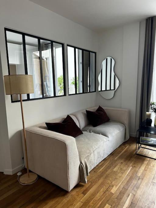 - un canapé blanc dans le salon doté de fenêtres dans l'établissement Appartement avec terrasse, à Paris