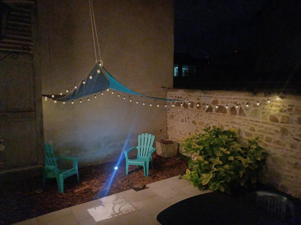 deux chaises vertes et des lumières dans un patio la nuit dans l'établissement Bel appartement tout équipé! Proche des parcs, avec sa cour privative et sa place de parking sécurisée à 450 m du logement, à Vichy