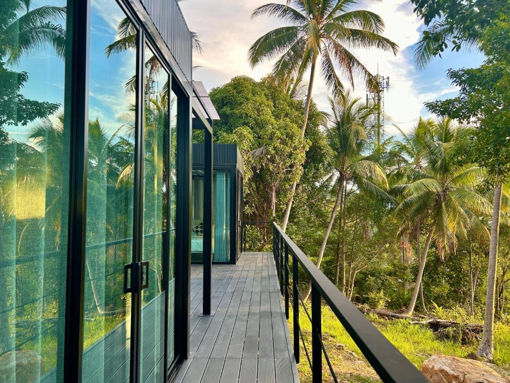 a glass walkway leading to a house with palm trees at Kalani, Haad Yao in Haad Yao
