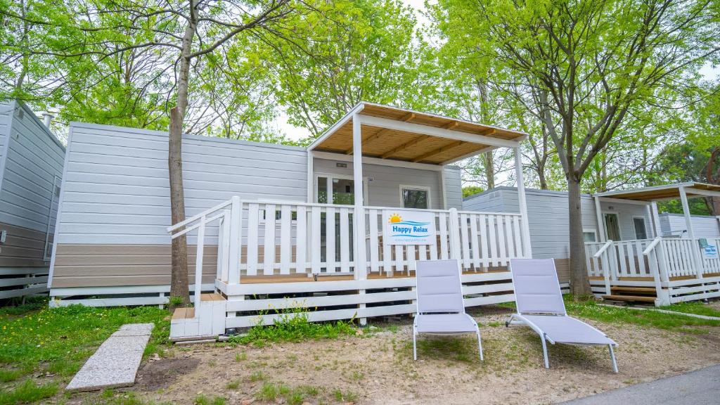 a tiny house with two chairs and a porch at Happy Camp mobile homes in Camping Bella Italia in Peschiera del Garda