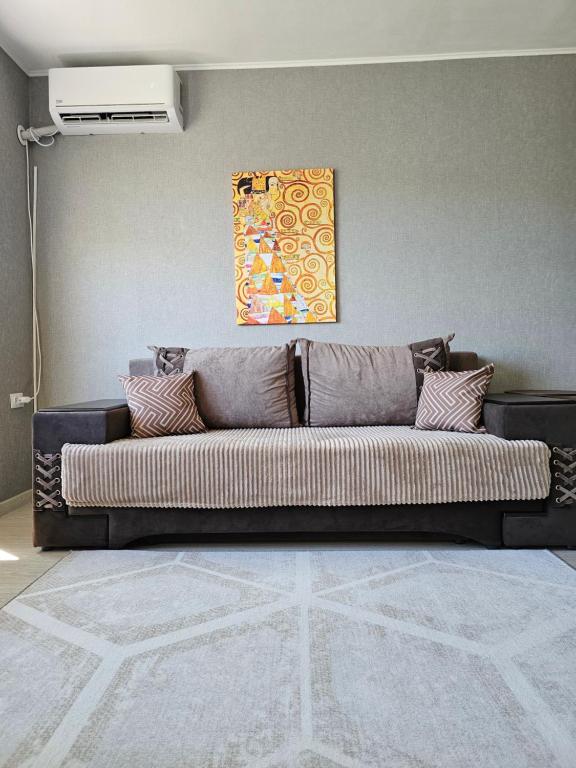 een bank in een woonkamer met een muur bij Квартира-студия рядом с Набережной in Balqash