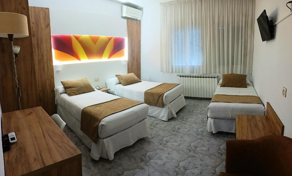 una habitación de hotel con dos camas y una mesa en Hostal Real, en Plasencia