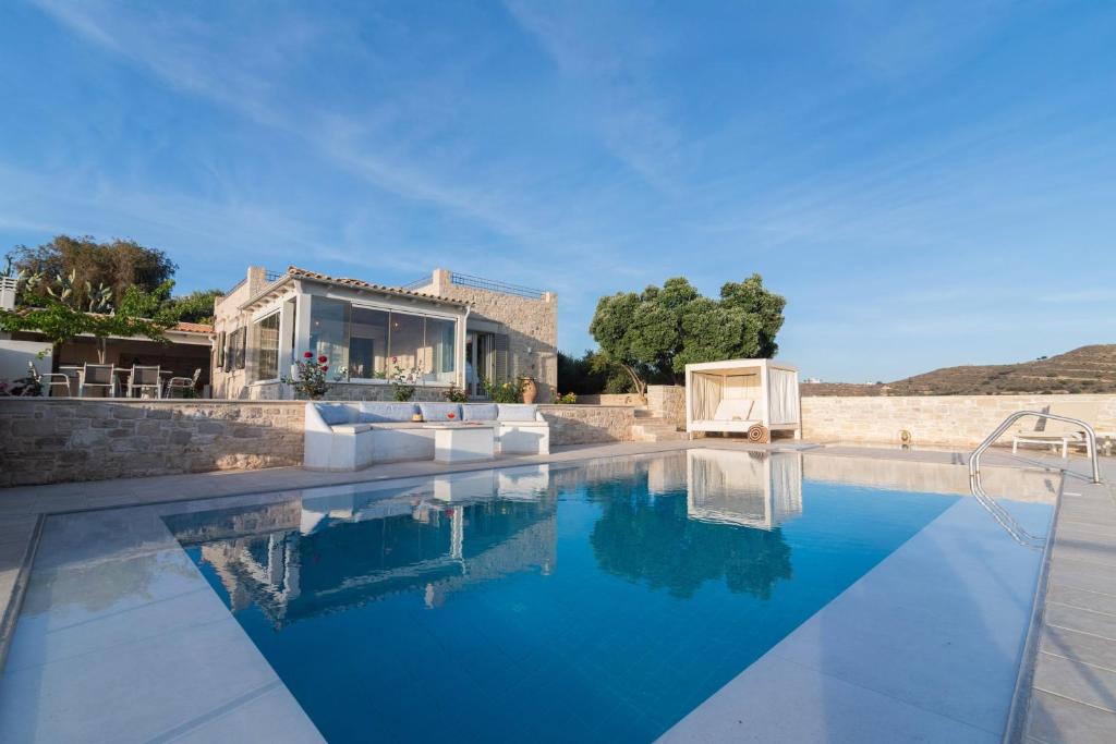 a villa with a swimming pool in front of a house at Koronio Villas in Kalamaki