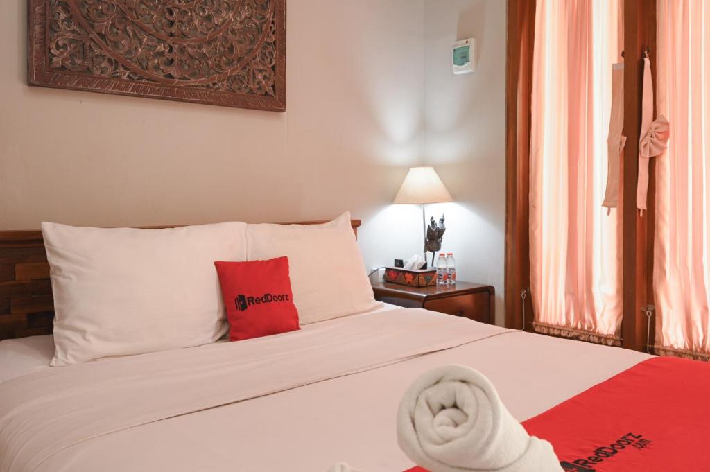 a bedroom with a white bed with a red pillow at RedDoorz near Mertasari Beach 2 in Pesanggaran
