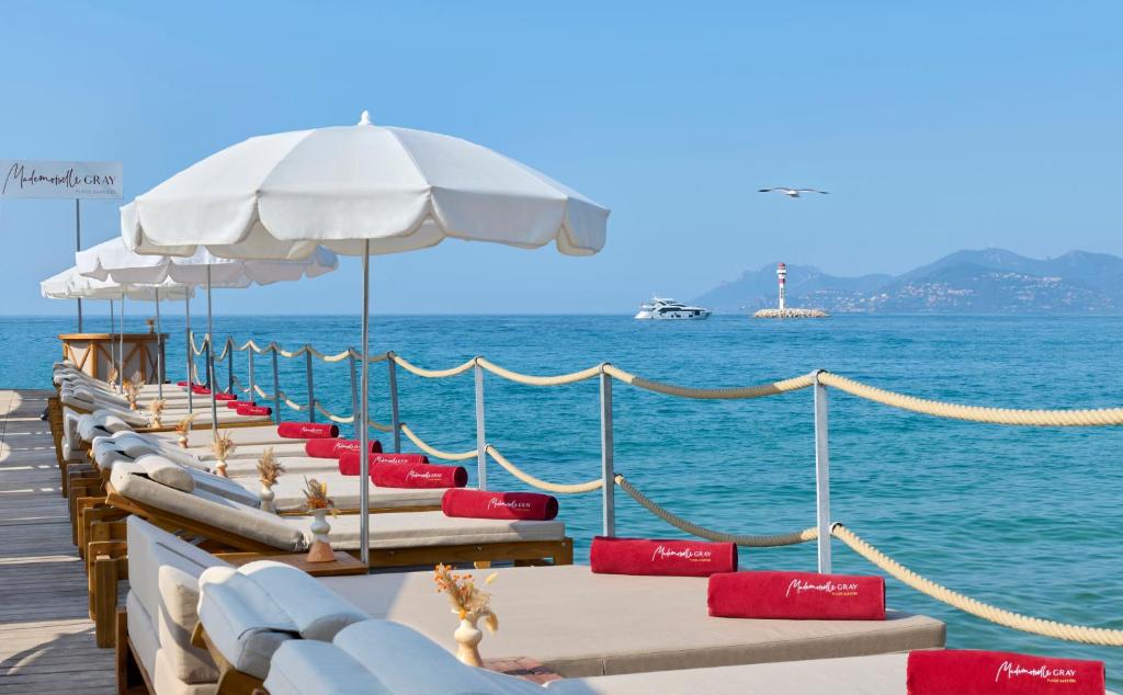 a row of beach chairs and umbrellas on a pier at Hôtel Barrière Le Gray d'Albion in Cannes