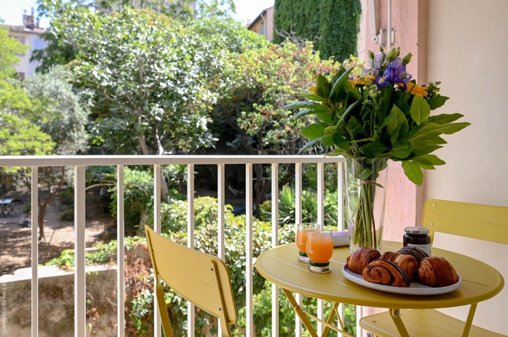 une table avec un vase de fleurs et une assiette de nourriture dans l'établissement Marseille Centre - Appartement 3 Chambres avec Balcon, à Marseille