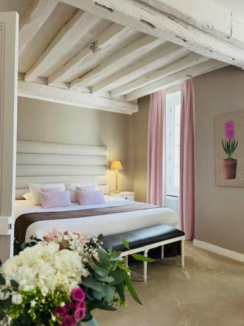 - une chambre avec un lit et des fleurs dans l'établissement Hôtel Saint-Laurent, The Originals Relais, à Montfort-lʼAmaury