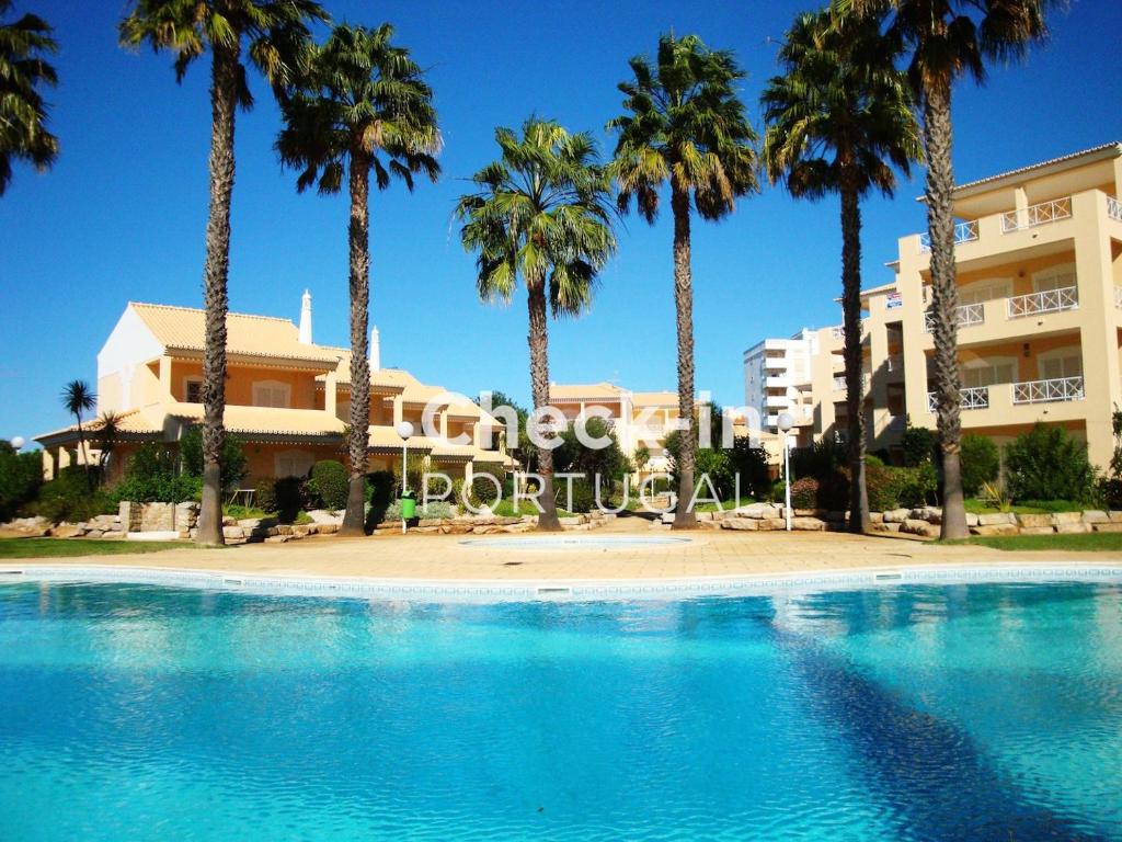 Una piscina con palmeras frente a un edificio. en Ellegance by Check-in Portugal, en Vilamoura