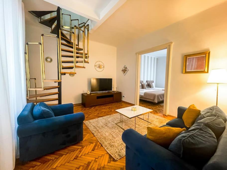 Sala de estar con 2 sofás azules y TV en Sweet House Skadarlija, en Belgrado