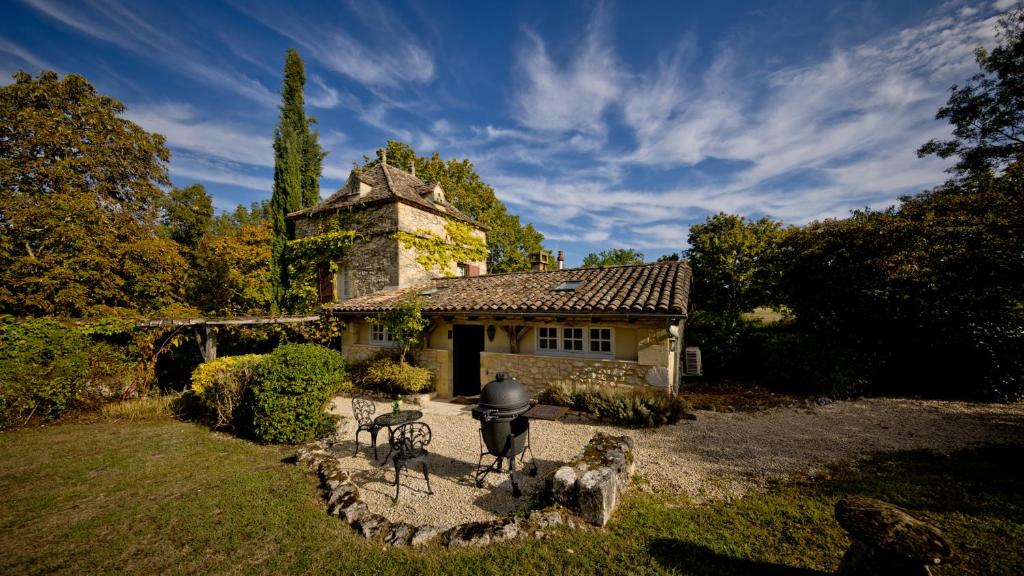 une maison en pierre avec une statue en face de celle-ci dans l'établissement Village des Éléments, à Naussannes
