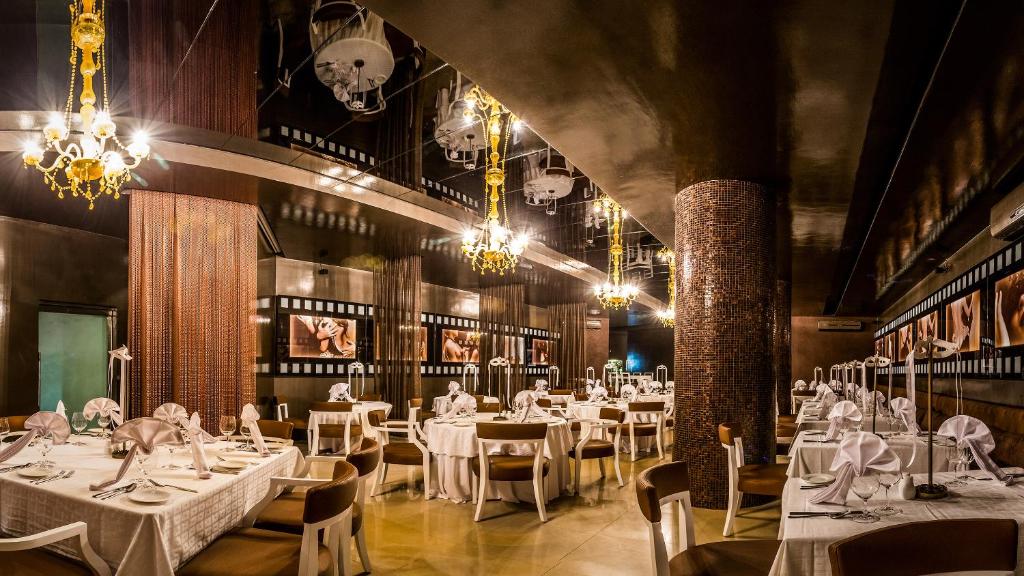 a restaurant with white tables and chairs and chandeliers at Desire Riviera Maya Resort All Inclusive - Couples Only in Puerto Morelos