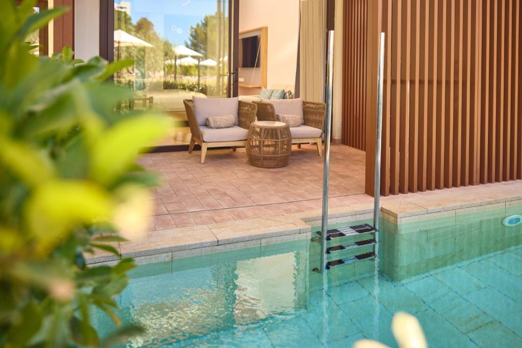 a swimming pool with two chairs next to a house at Cala San Miguel Ibiza Resort, Adults only, Curio Collection by Hilton in Puerto de San Miguel