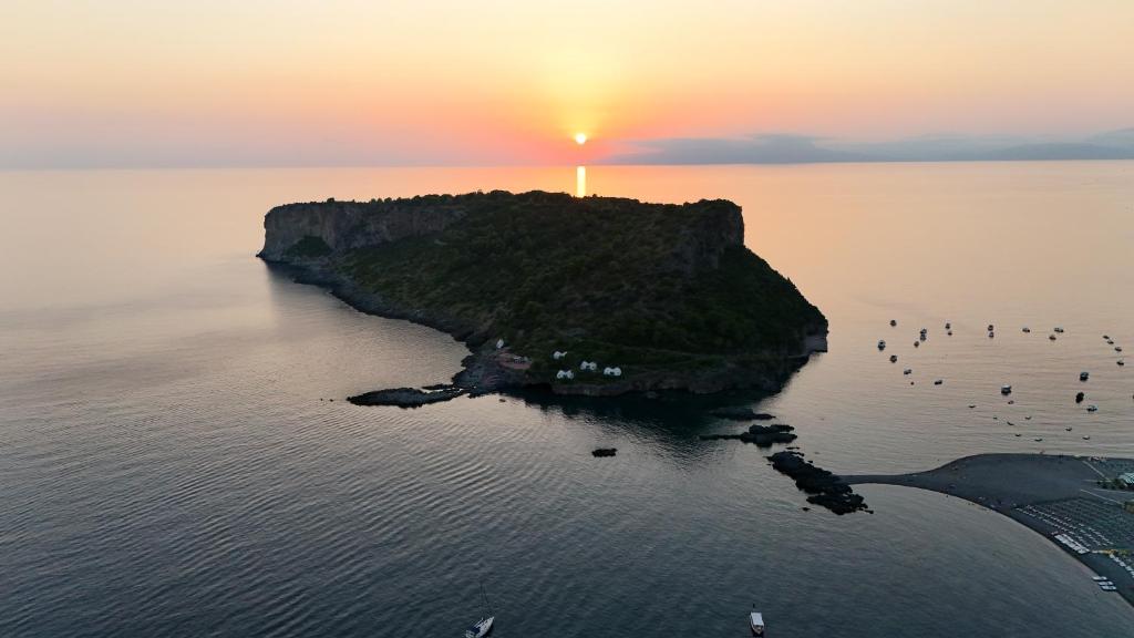 an island in the ocean with a sunset in the background at La casa del Tramonto in Praia a Mare