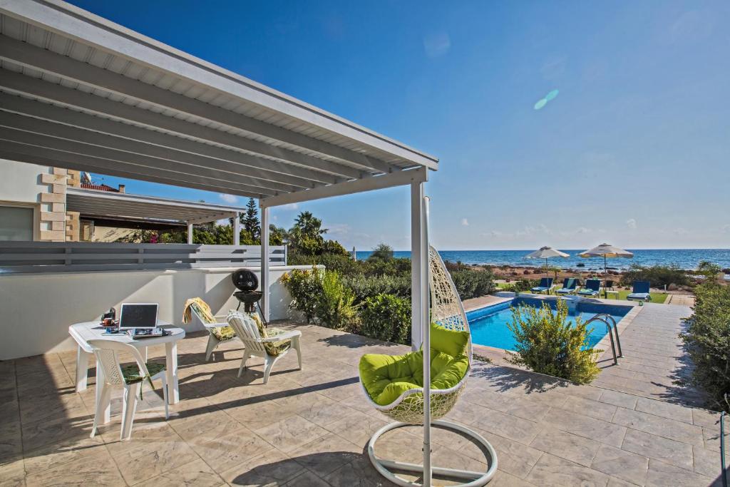 une terrasse avec une table et des chaises et l'océan dans l'établissement Gorgona Villas, à Ayia Napa