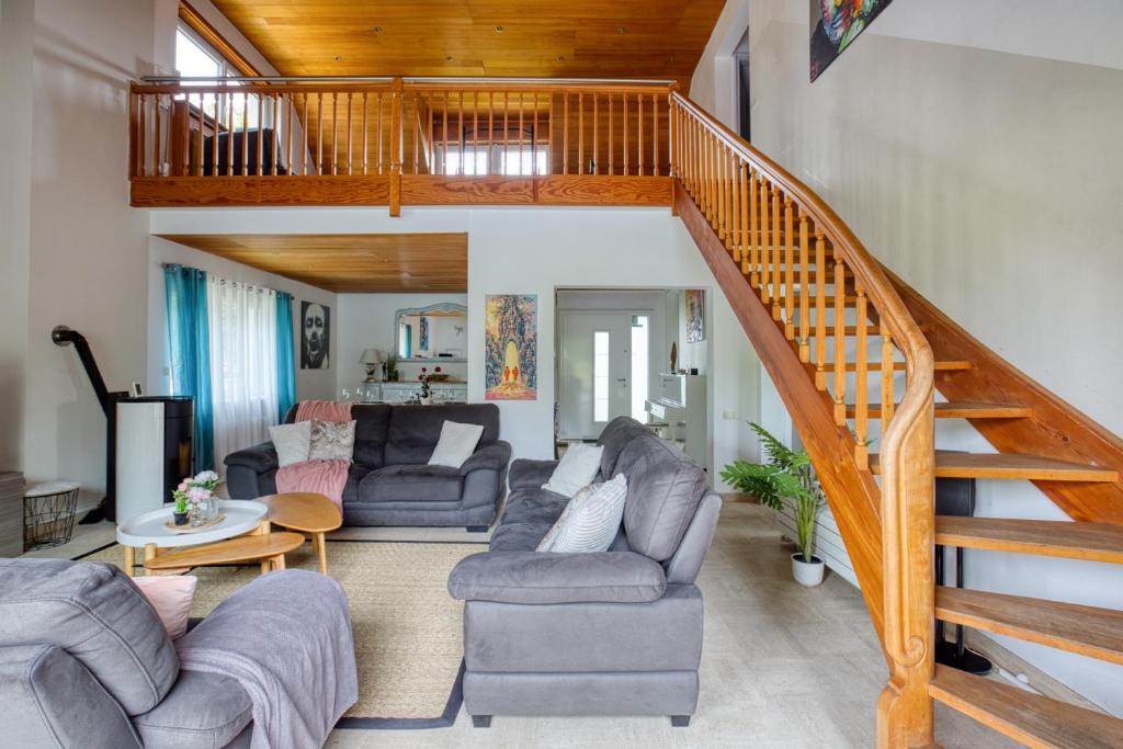 a living room with couches and a wooden staircase at Jolie Villa, 300 m2, grand jardin in Furdenheim
