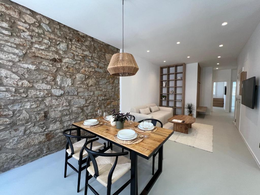 a dining room with a table and a stone wall at Apartamento completo ideal para estancias y trabajo - Ferrol by Miramar Stays in Ferrol