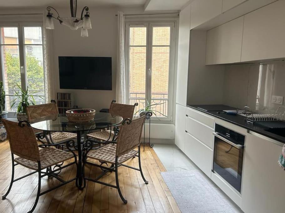 une cuisine avec une table et des chaises dans une pièce dans l'établissement Beautiful contemporary and cosy flat in Paris, à Boulogne-Billancourt