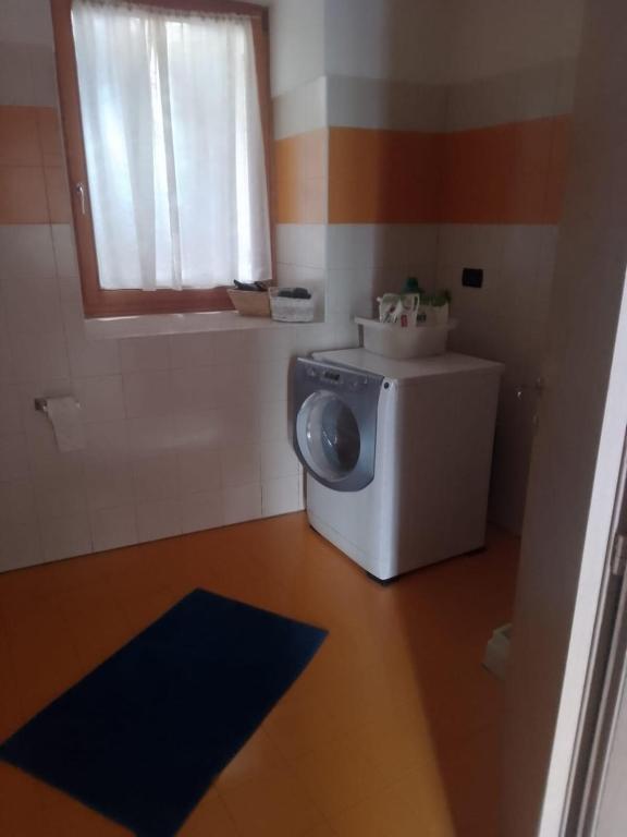 niewielka łazienka z pralką i oknem w obiekcie la farfalla di Susà w mieście Pergine Valsugana