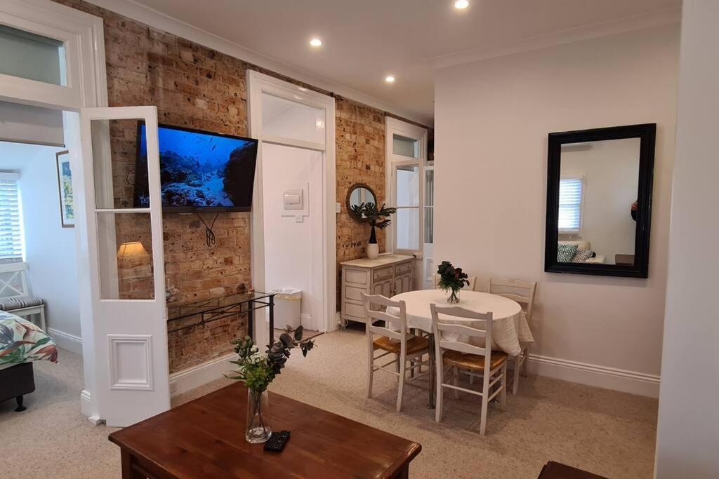 Una sala de estar con una mesa y un comedor. en Beachfront Sunset View Apartment - The Coachhouse, en Narrabeen