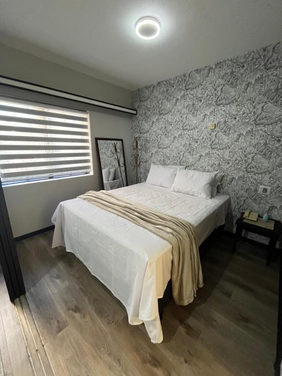 Hotel FlatScape - Flat Aconchegante no The Time - BTT, a bedroom with a large white bed with a stone wall at FlatScape - Flat Aconchegante no The Time - BTT in São Paulo