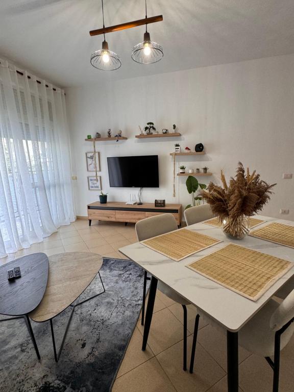 Una sala de estar con una mesa y sillas y un televisor. en DR Apartment, en Golem